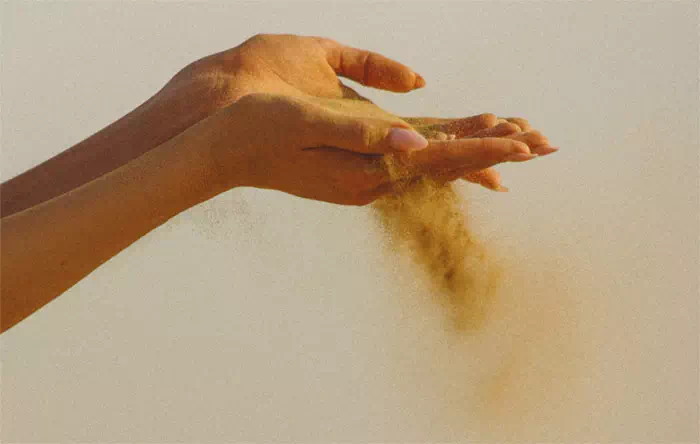 Sand fällt durch Hand