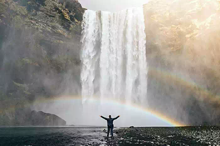 Mann steht vor Wasserfall